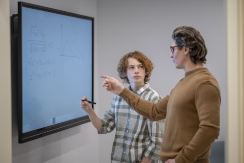 maths lesson ginger boy writing board teacher standing him