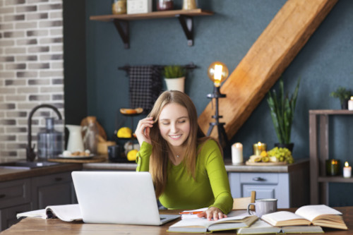 portrait smiling young woman using phone while sitting table